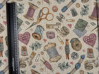 Fabric with sewing-themed pattern including spools of thread, scissors, and thimbles on a beige background.