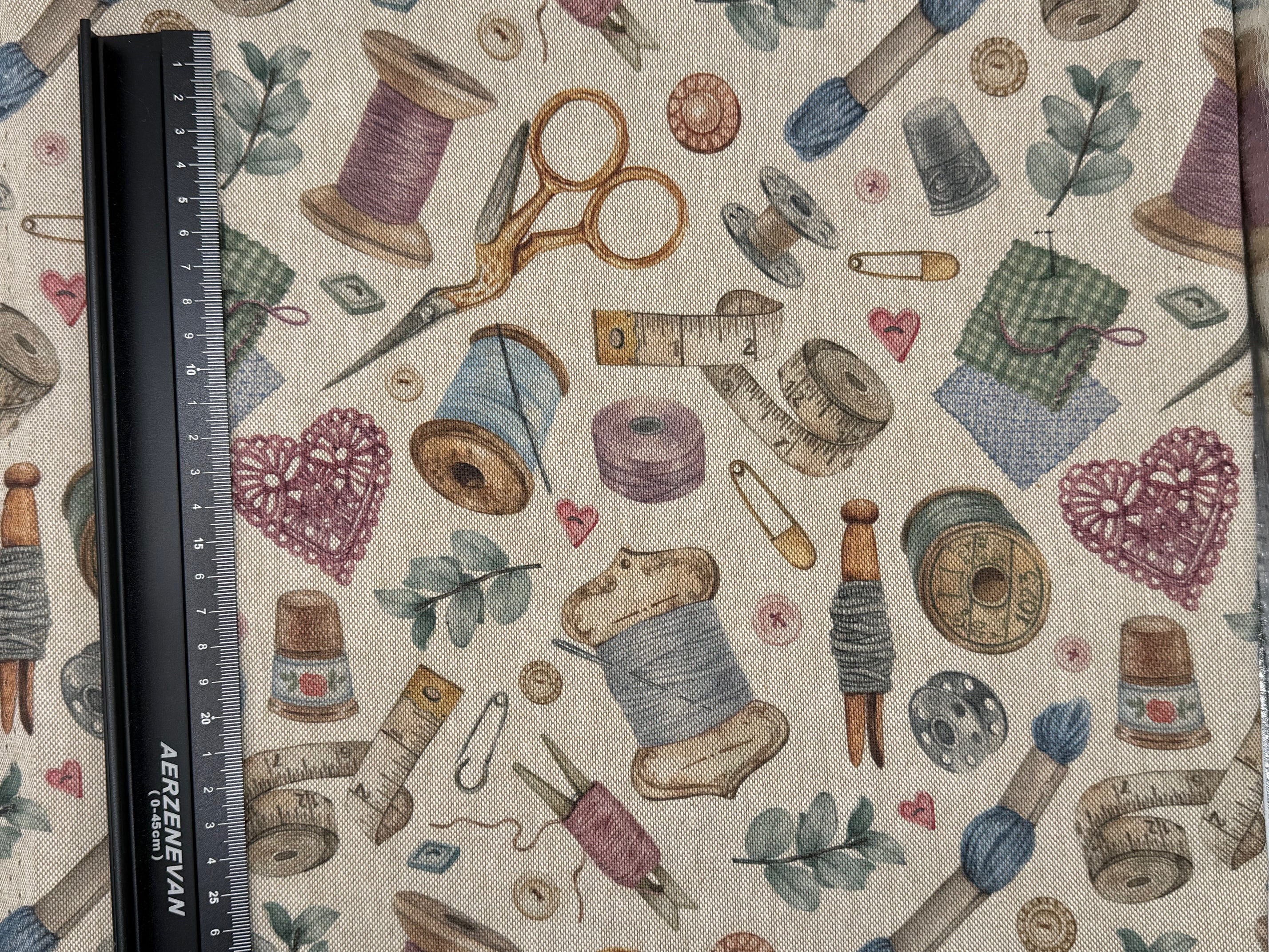 Fabric with sewing-themed pattern including spools of thread, scissors, and thimbles on a beige background.