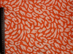 Fabric with a animal print pattern on an orange background, measured by a ruler.