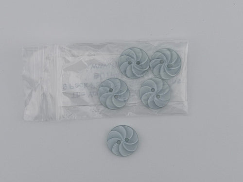 Four small round spiral-shaped buttons in a pale blue-gray color, with one button placed to the left of a clear plastic bag containing the remaining three buttons.