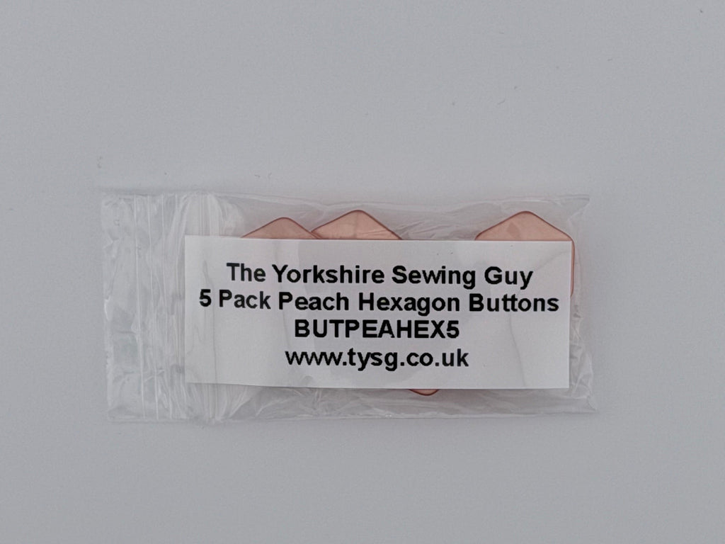A small clear plastic bag containing five peach-colored hexagon buttons, with a white paper label that reads 'The Yorkshire Sewing Guy 5 Pack Peach Hexagon Buttons BUTPEAHEXS www.tysg.
