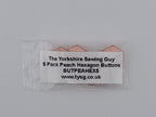 A small clear plastic bag containing five peach-colored hexagon buttons, with a white paper label that reads 'The Yorkshire Sewing Guy 5 Pack Peach Hexagon Buttons BUTPEAHEXS www.tysg.