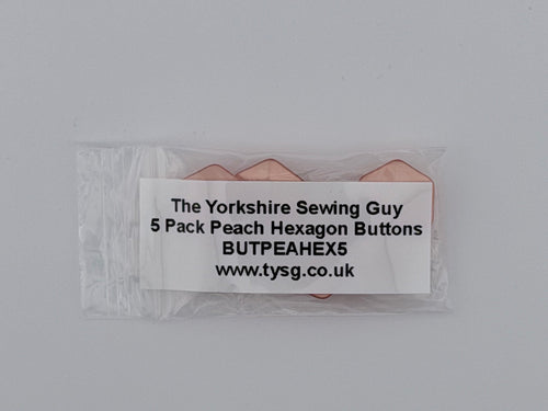 A small clear plastic bag containing five peach-colored hexagon buttons, with a white paper label that reads 'The Yorkshire Sewing Guy 5 Pack Peach Hexagon Buttons BUTPEAHEXS www.tysg.