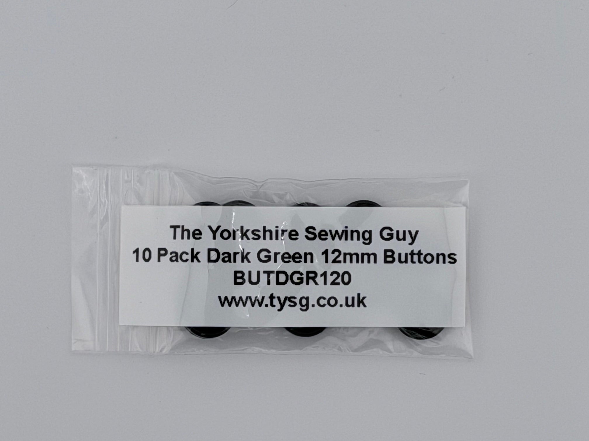 A clear plastic bag containing 10 dark green 12mm sewing buttons, with a white paper label showing the brand 'The Yorkshire Sewing Guy' and product details, set against a plain light gray background.